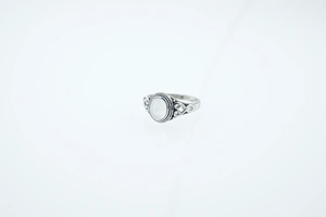 Detailed close-up of retro silver ring featuring a white oval stone and hollow carvings