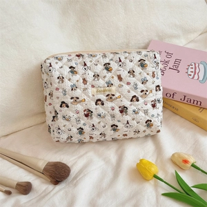 Close-up of quilted cosmetic bag with colorful cartoon dog prints and gold zipper