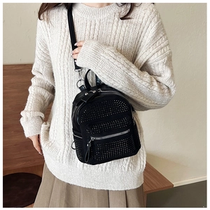 Detalle de una mini mochila negra para mujer decorada con pedrería y tachuelas