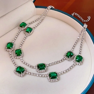 Macro detail of silver tone layered necklace with rectangular emerald green stones