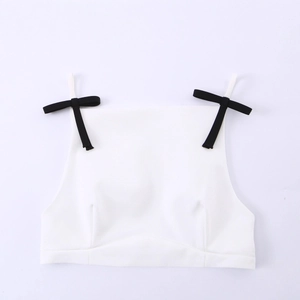 Witte mouwloze crop top met zwarte strikjes op de schouderbandjes op een witte achtergrond