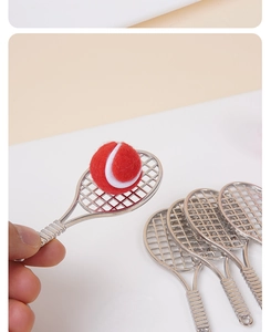 Mini racchette da tennis in metallo argento e pallina rossa tenute in mano