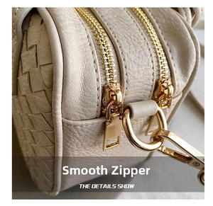 Detailed macro view of lychee leather texture and golden zippers on a woven handbag