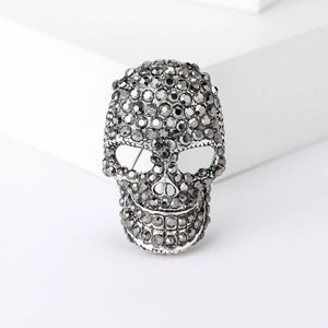 Silver skull brooch with dark grey rhinestones on a clean white background