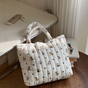 Detail of white quilted handbag featuring brown bear prints and simple wish patch
