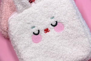 Close-up of white plush sanitary napkin bag with cute rabbit embroidery and pink zipper