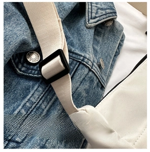 Detail of white nylon shoulder bag featuring a black plastic buckle and woven strap