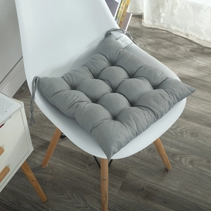 Detail of dark grey quilted chair pad with 16 tufted points and tie-on straps on a white chair