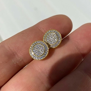 Classic round gold-plated stud earrings with pavé-set cubic zirconia held by hand