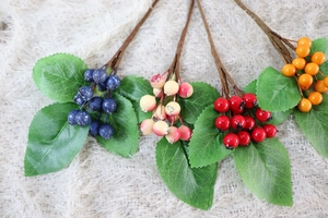 Detailed close-up of artificial holly berries in four colors on soft plush background