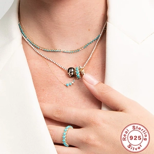 Detail of 925 sterling silver layered necklace with turquoise moon pendant on model