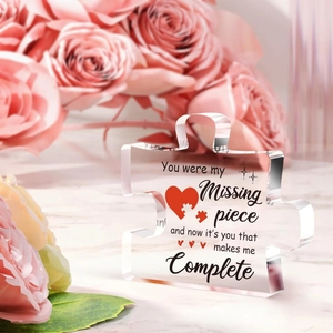 Close-up of heart-themed clear acrylic puzzle ornament on a marble surface with roses