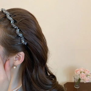 Detailed view of wavy rhinestone headband and matching pearl jewelry on a female model