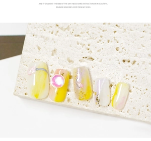 Close-up of pink and yellow marble nail art tips with gold foil on beige stone