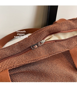 Detail of a brown woven tote with smooth silver zipper closure and soft beige lining