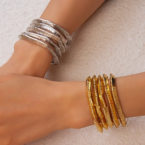 Close-up of stacked gold and silver metal bangles with fine horizontal textures