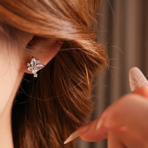 Gros plan d'une boucle d'oreille papillon argentée avec zircons portées par un modèle