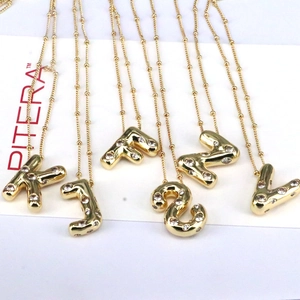 Detail of 18k gold plated bubble letter pendants with pave cubic zirconia on beaded chains