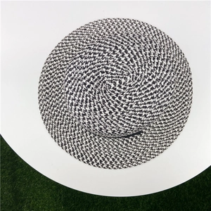 Top-down view of a flat top straw hat with black and white woven fibers and black ribbon