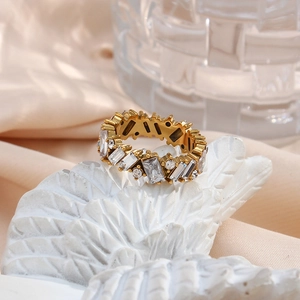 Macro shot of gold zircon ring featuring mixed-cut clear stones on white feather