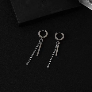 Macro detail of silver tassel chain earrings with rectangle pendants on leather