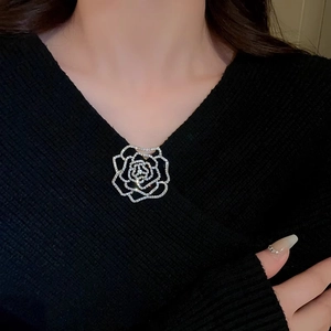 Close-up of a silver rose brooch with cubic zirconia on a black V-neck sweater
