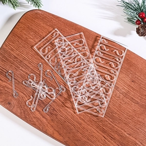 Close-up of clear S-shaped plastic hooks for Christmas tree ornaments on a wooden board