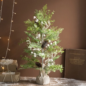 Mini forest style Christmas tree with white antlers and pine cones in burlap base