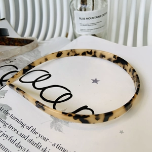 Detailed view of leopard print acetate headband resting on a magazine in soft light