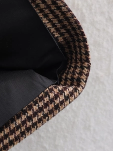 Detailed close-up of brown houndstooth wool fabric and smooth black inner lining