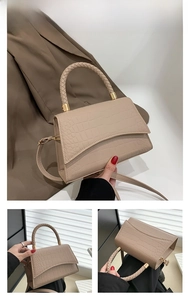 Detail view of khaki crocodile pattern handbag with woven handle and gold hardware