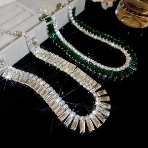 Detailed close-up of emerald and clear rectangular crystal fringe necklaces with metal chain