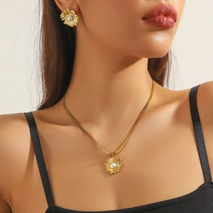 Close-up of gold-plated sunflower jewelry set with pearls and turquoise on a model