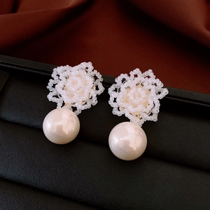 Macro detail of handmade floral bead earrings with elegant round drop pearls