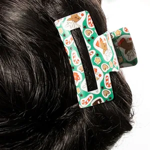 Green Christmas hair claw clip with reindeer and candy cane patterns on dark hair