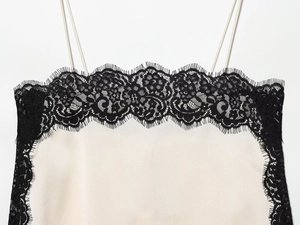 Détail d'un caraco en satin ivoire montrant la dentelle noire et les fines bretelles