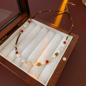 Detail of vintage tiger eye and pearl beaded necklace displayed in a premium wooden box
