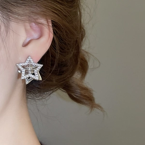 Close-up of star-shaped silver zircon earrings worn by a model in a side view
