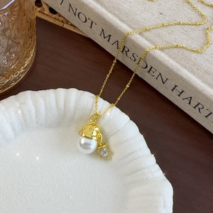 Elegant gold Christmas hat necklace with pearl and star pendant on a white ceramic plate
