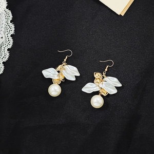 Detail shot of vintage pearl petal earrings with gold finish and white resin charms