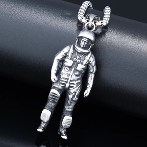 Macro shot of silver astronaut pendant on a square pearl chain with industrial texture