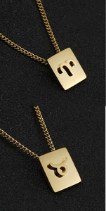Macro detail of Aries and Taurus zodiac pendants in 18K gold plated stainless steel