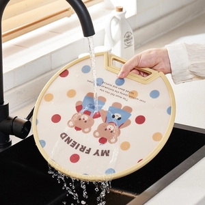 Standing round PE cutting board with bear pattern and handle being rinsed under water