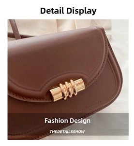 Close-up of a dark brown leather saddle bag with gold cylinder buckle and neat stitching