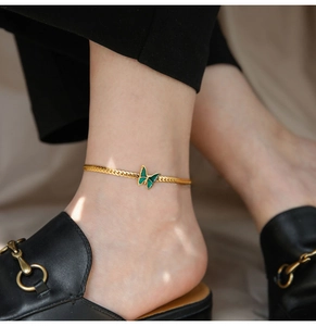 Detailed view of an 18K gold plated snake chain anklet featuring a green butterfly charm