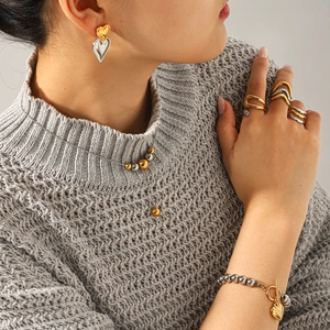 Two-tone heart-shaped jewelry set with necklace, bracelet, and rings on grey sweater
