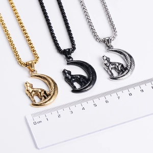 Three Viking wolf crescent moon pendants in gold, black, and silver with ruler for scale