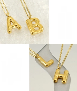 Gros plan sur les pendentifs lettres bombées A, B, L, H en acier inoxydable doré brillant