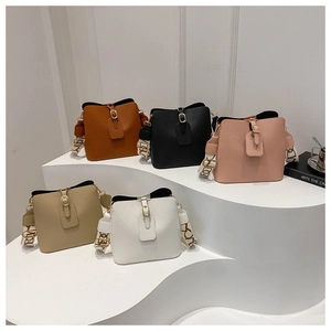 Group shot of bucket bags in five colors with patterned wide straps on a pedestal