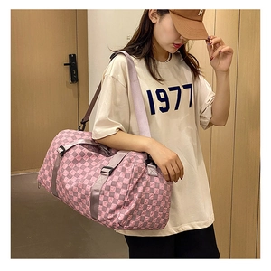 Close-up of a pink checkerboard large capacity travel duffel bag shown on a model